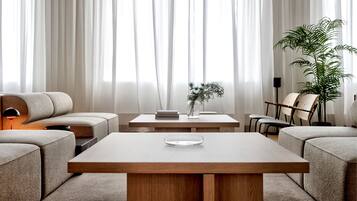 A modern living room with a sofa, a coffee table, and a chair. There is a plant on the table and another on the floor.