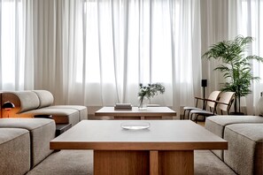 A modern living room with a sofa, a coffee table, and a chair. There is a plant on the table and another on the floor. - Habyt Berlin Waterfront (Berlin)