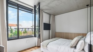 A modern bedroom with a large window, a bed, a TV, and a view of the outside. - Habyt Berlin Waterfront (Berlin)