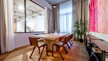 Un salón de conferencias con una gran mesa de madera, seis sillas y una planta en maceta.