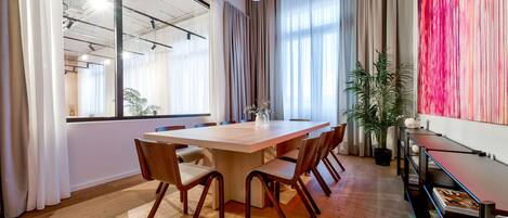 Une salle de conférence avec une grande table en bois, six chaises et une plante en pot.