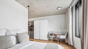 A modern hotel room with a large bed, a desk, and a kitchenette. - Habyt Berlin Waterfront (Berlin)