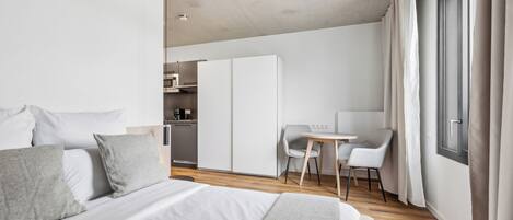 Una habitación de hotel moderna con una cama grande, un escritorio y una kitchenette.