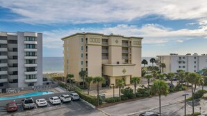 Ein mehrstöckiges Hotel mit Pool, Parkplätzen und Blick auf den Strand.