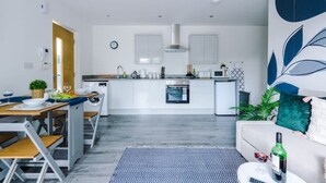 Una cocina moderna con armarios blancos, horno empotrado y microondas.