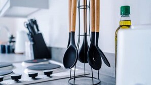 Una cocina con un portalapices que contiene cucharas negras y una botella de aceite.