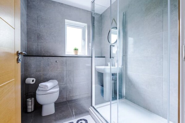 A modern bathroom with a toilet, sink, and glass shower enclosure.