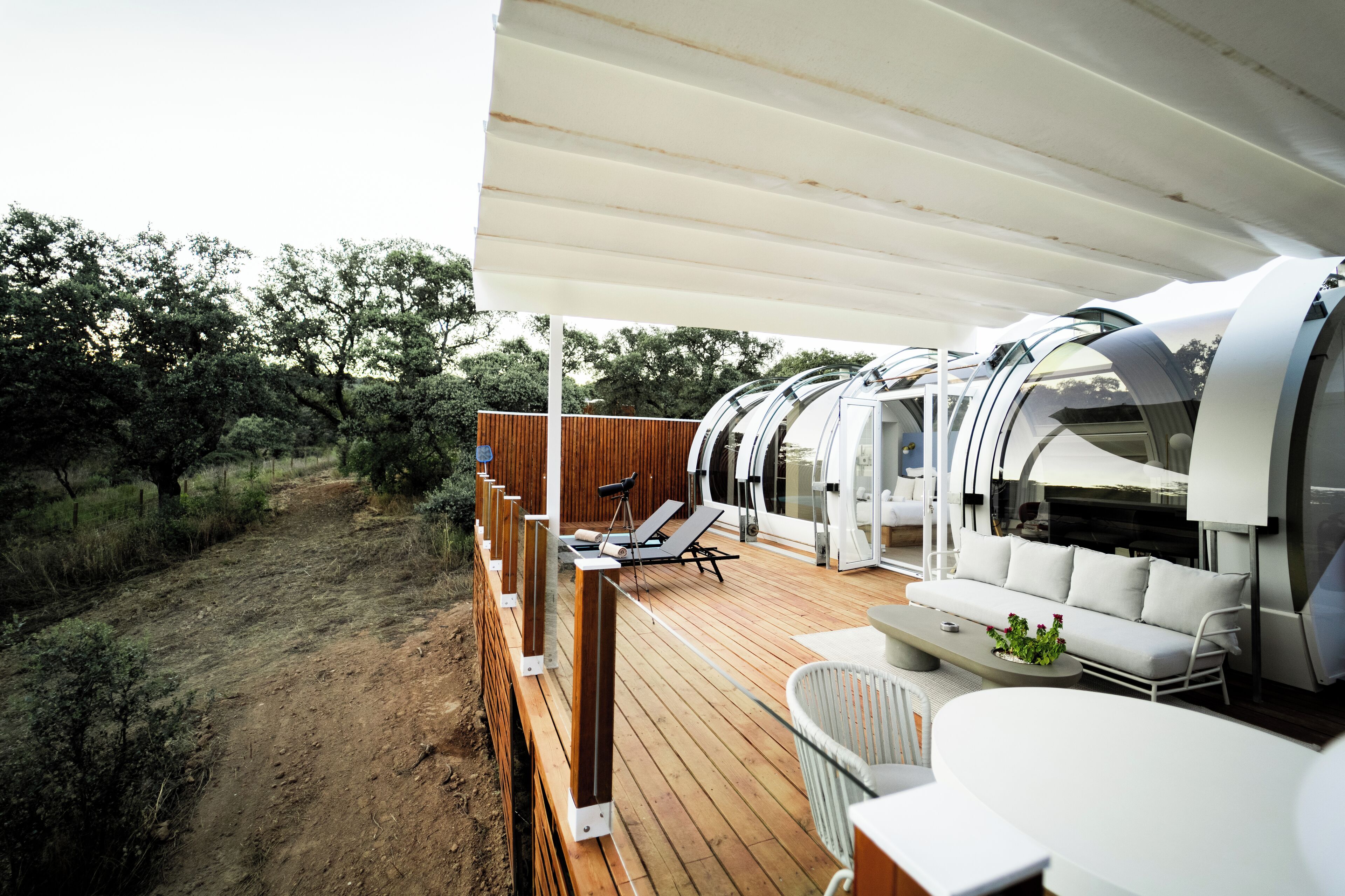 A deck with a white sofa, a dining table, and a lounge chair.