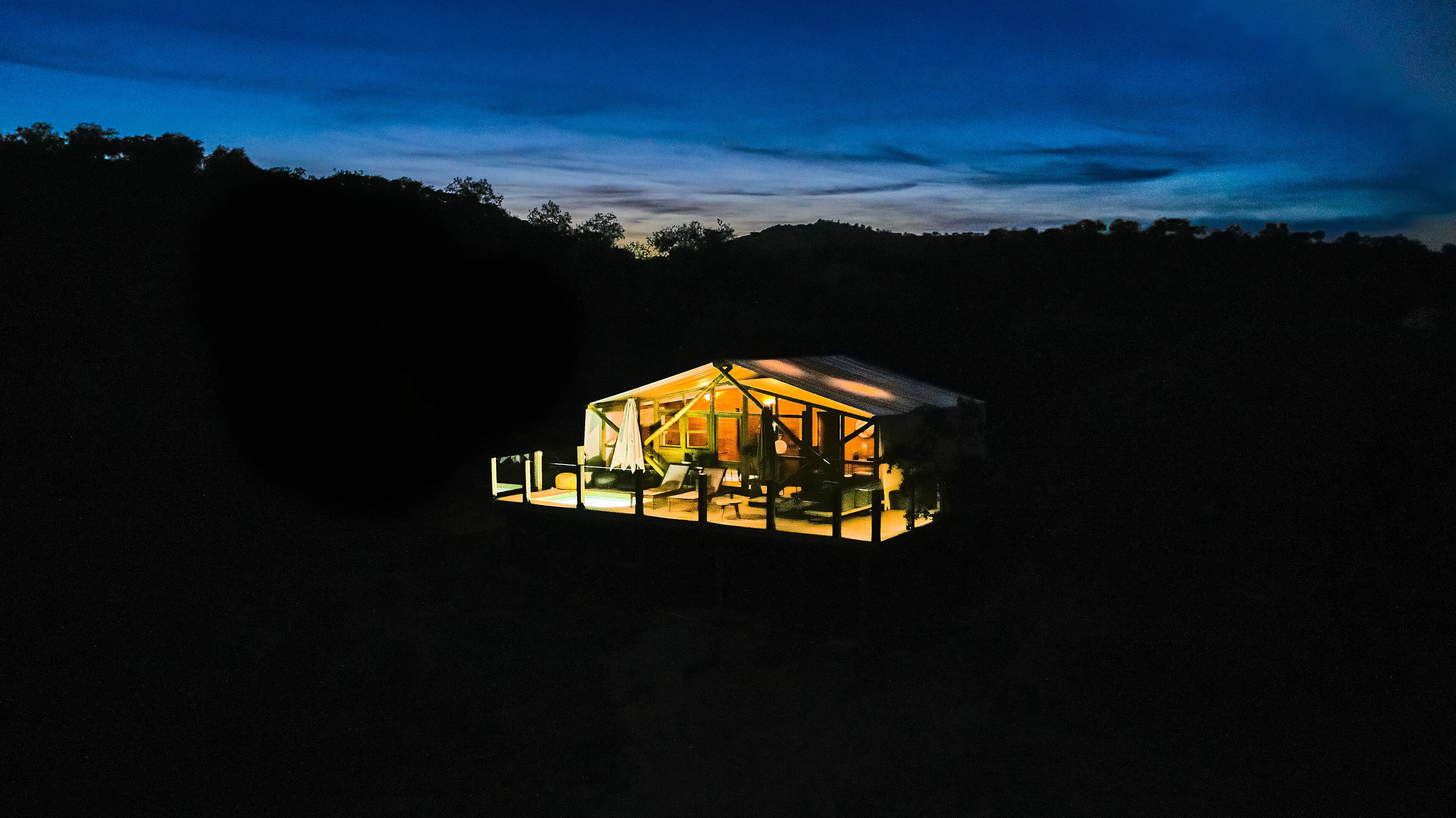 Une cabane en bois dotée d’un grand espace intérieur ouvert, d’une véranda et d’une fenêtre bien visible.