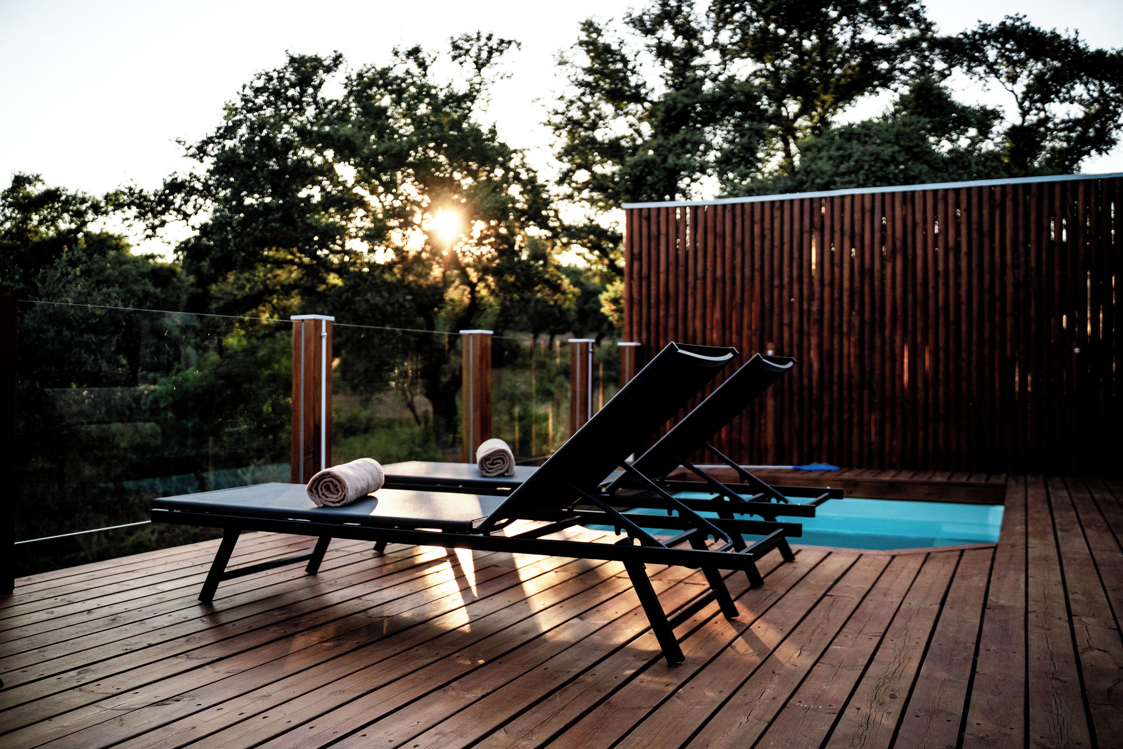 Una terraza de madera con sillones de descanso y una piscina pequeña.