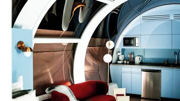 A modern interior with a bed, red sofa, and a kitchenette.