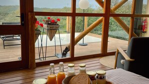 A breakfast tray with various food items on a wooden table in a room with large windows. - La Dehesa Experiences (Adamuz)