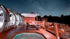 A modern outdoor deck with a hot tub, lounge chairs, and a covered seating area under a starry sky. - La Dehesa Experiences (Adamuz)