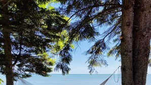Un hamac tendu entre deux arbres, avec vue sur une plage.