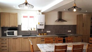 Een moderne keuken met houten kastjes, een magnetron, een spoelbak en een eettafel met stoelen.