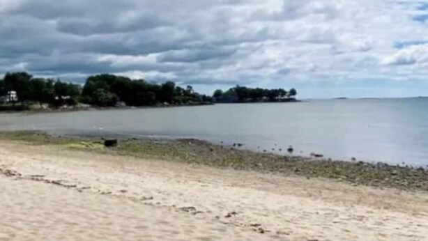 En strand med en sandstrand och ett lugnt vattenområde.