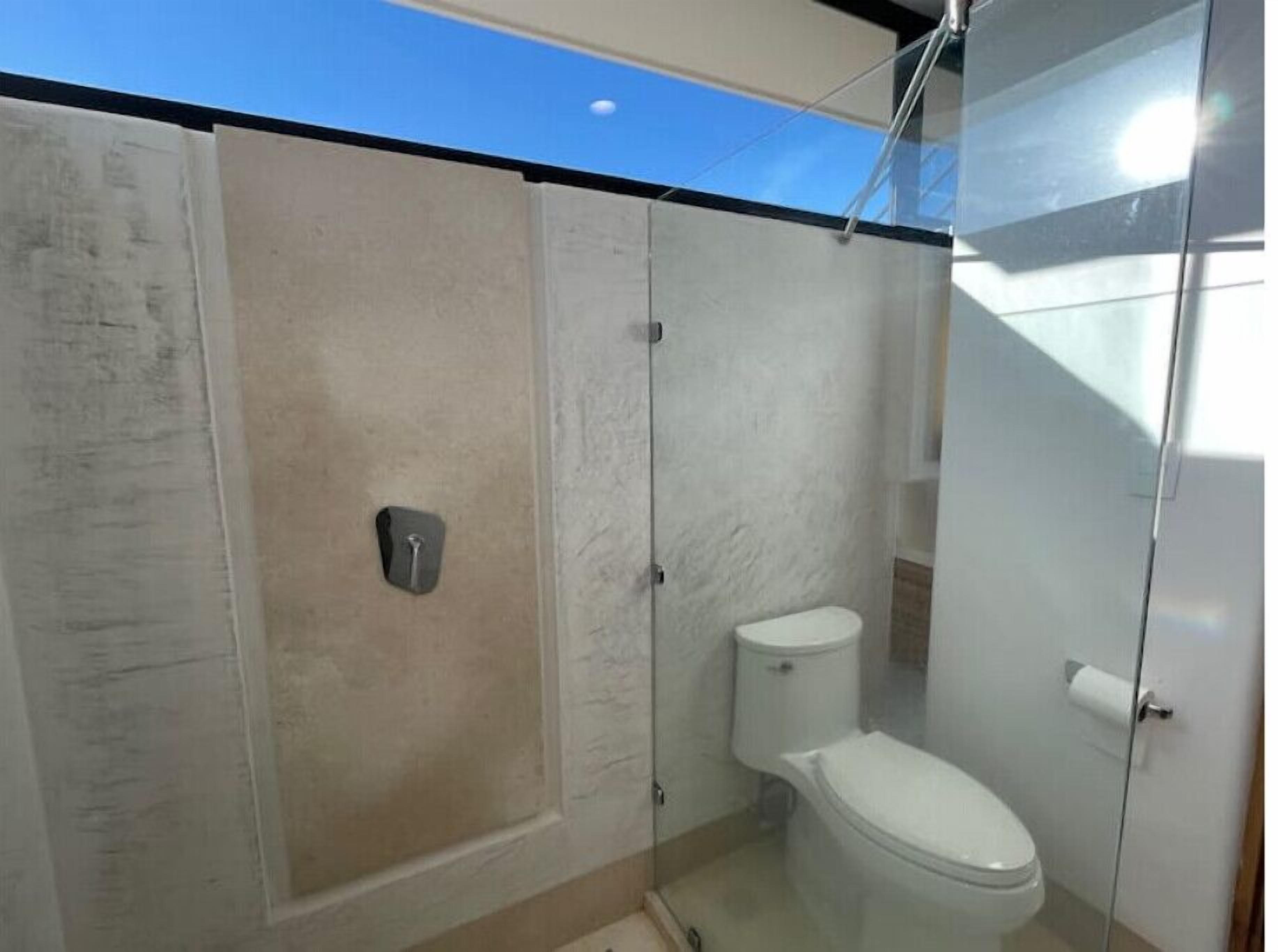 Un baño con cabina de ducha de vidrio, inodoro y lavamanos.