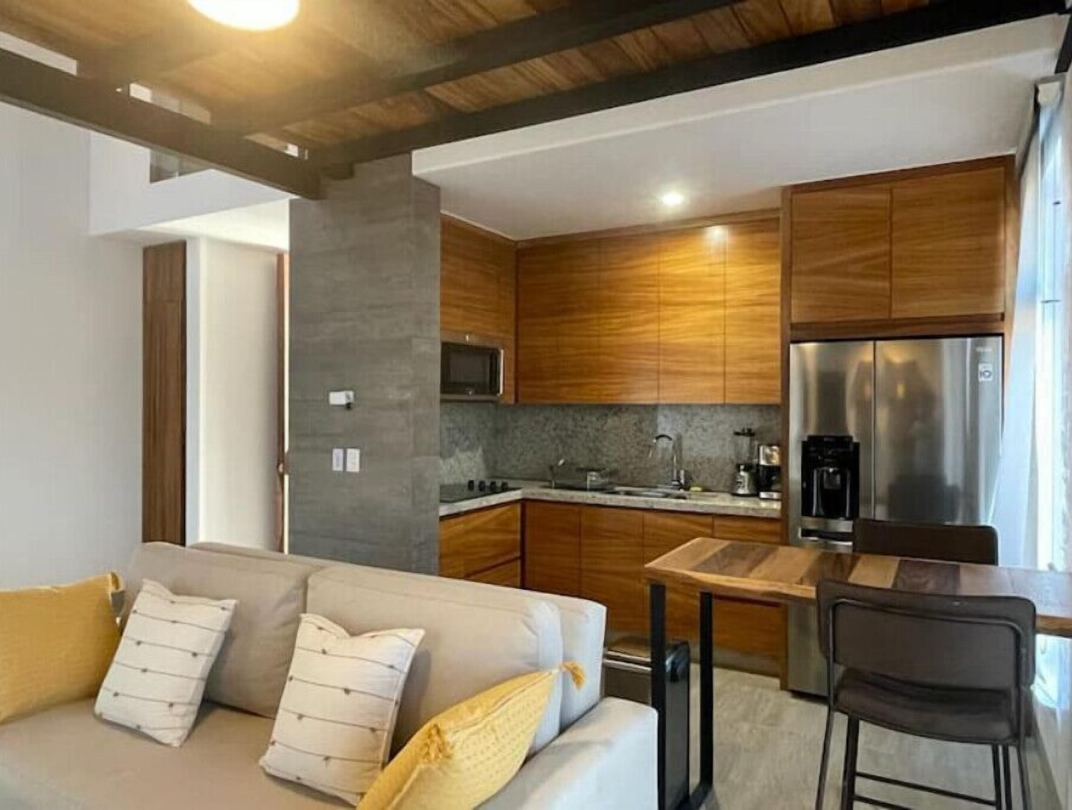Una cocina moderna con armarios de madera, un refrigerador de acero inoxidable y un microondas integrado.