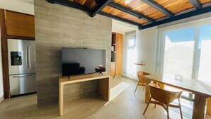A modern kitchen with a built-in TV, wooden cabinets, and a dining area with a table and chairs.