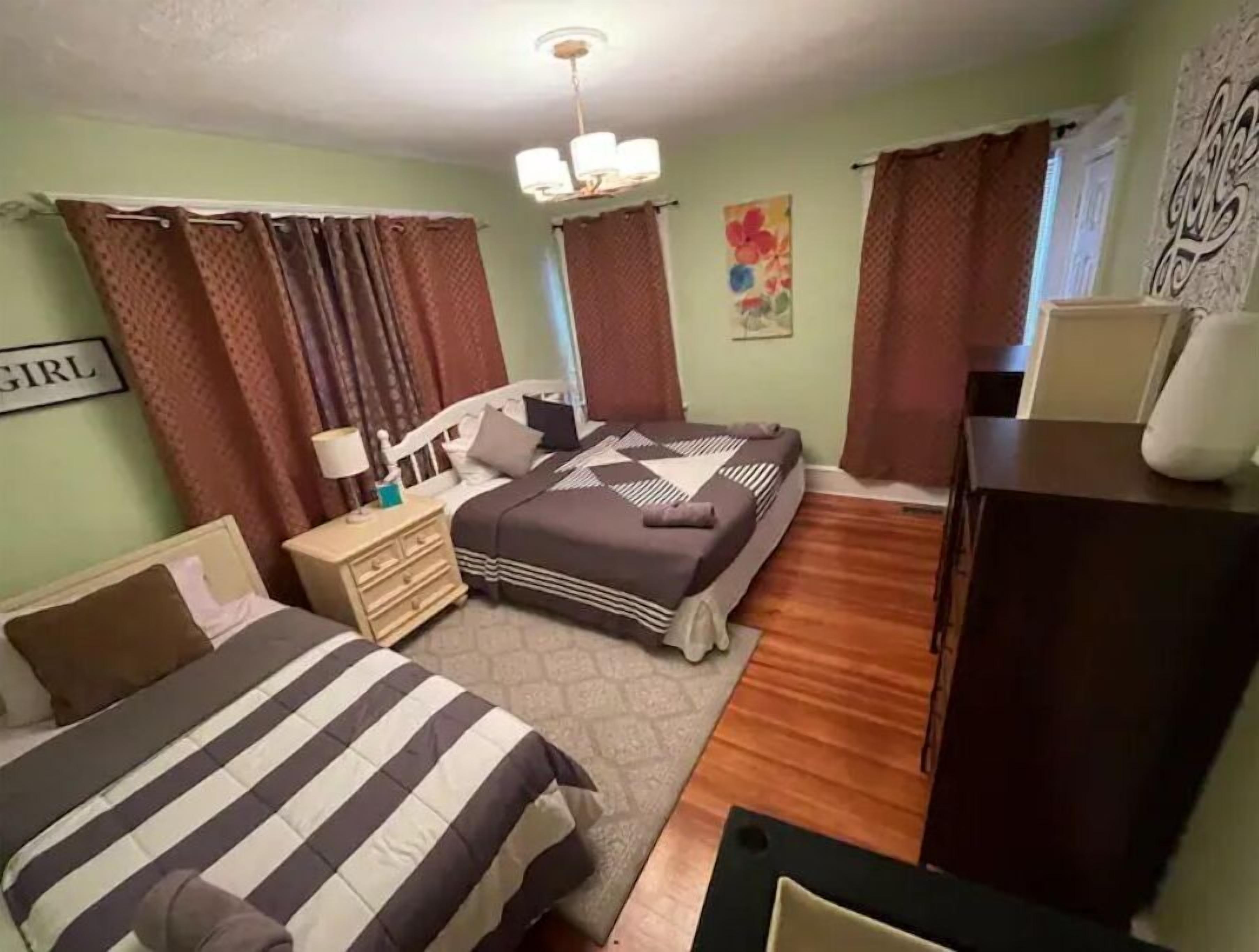 Een kamer met twee bedden, een kaptafel, een nachtkastje, een kroonluchter en een schilderij aan de muur.