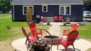 A house with a patio area featuring a fire pit and red chairs.