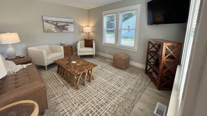 A living room with a ceiling fan, a sofa, a coffee table, a chair, a lamp, a TV, and a window with blinds.