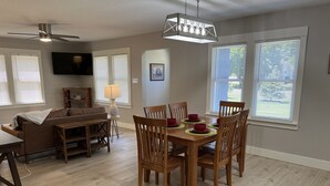 A dining area with a wooden table and chairs, a ceiling fan, and a chandelier.