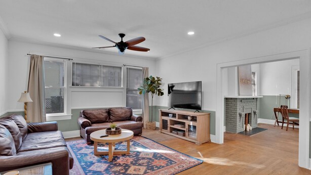 A spacious living room with a leather sofa, a coffee table, a TV, and a fireplace. - The Arrive on Rutherford (Shreveport)
