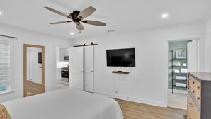 A bedroom with a bed, a ceiling fan, a TV, and a walk-in closet. - The Arrive on Rutherford (Shreveport)