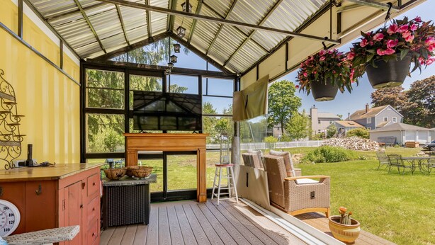 Un espace extérieur abrité, avec un banc en bois, une petite table et des jardinières suspendues.