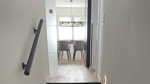 A staircase with black steps leading to a dining area with a table and chairs.
