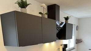 A modern kitchen with dark cabinets, a built-in oven, and a countertop with a coffee maker.