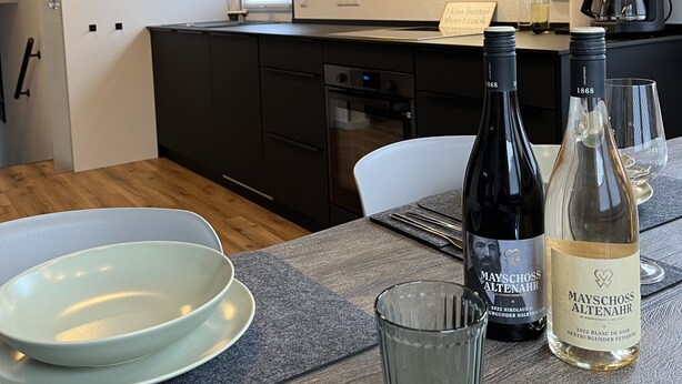A modern kitchen with dark cabinetry, a coffee maker, and two wine bottles on the counter.