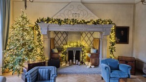 Une pièce chaleureuse avec une cheminée, un sapin de Noël et deux fauteuils.