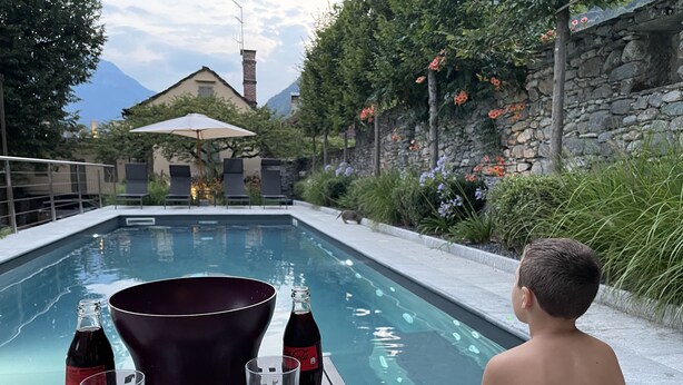 Une scène au bord de la piscine, avec une table sur laquelle se trouvent un seau, deux bouteilles et deux verres.