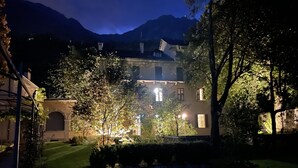 Un bâtiment doté d’un jardin, d’une arche en pierre et avec une montagne en arrière-plan.