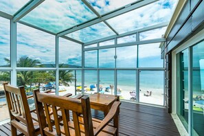 A covered outdoor seating area with a view of the beach and ocean. - Triplex Pé na Areia - Bombinhas (Bombinhas)