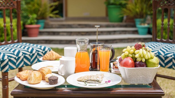 Ein Frühstückstisch mit Croissants, einer Obstschale, einem Orangensaftkrug und einer Kaffeekanne.