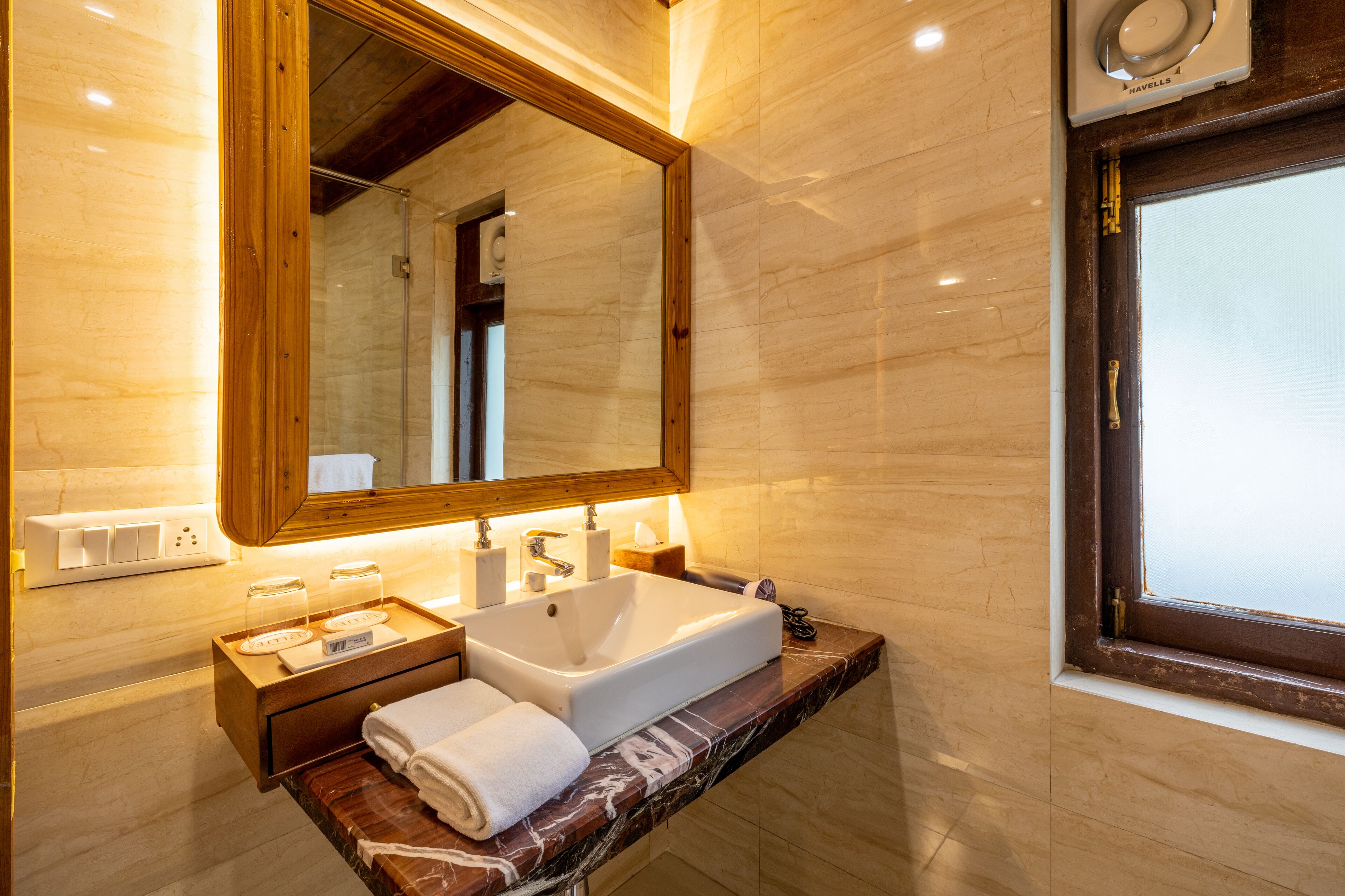 A bathroom with a marble countertop, a large mirror, a sink, and a window.
