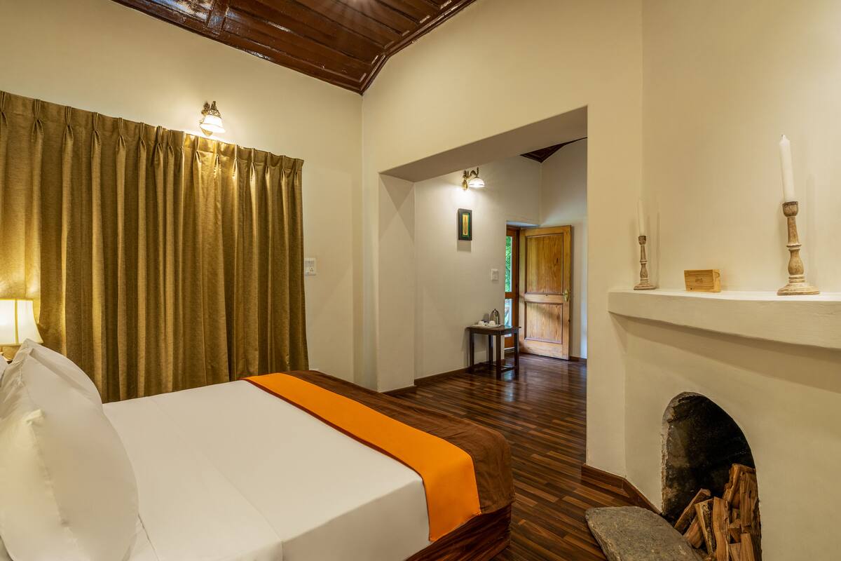 A hotel room with a bed, a fireplace, and a hallway leading to another room.