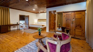 Una habitación amplia con suelo de madera, una cama, un escritorio y una silla.