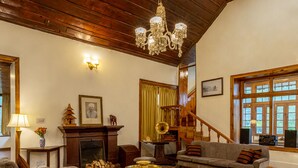 Un salón amplio con chimenea, suelo de madera y una alfombra roja grande.