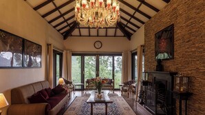 Un salón espacioso con una gran lámpara de araña, una chimenea y vistas a través de puertas de cristal.