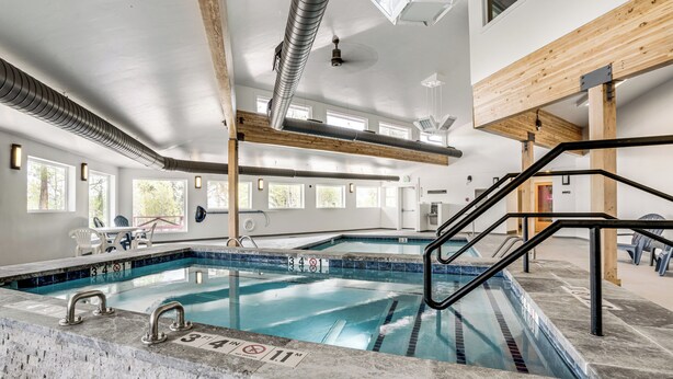 Una piscina con corsie ben delimitate, un trampolino e una struttura a soffitto in legno.