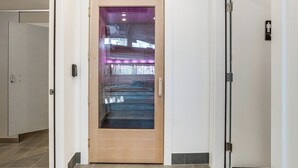 Un interno moderno con una porta in legno, un pavimento piastrellato e un ascensore in vista.