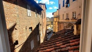 Una calle estrecha con tejados de teja terracota y edificios de piedra, vista desde una ventana.