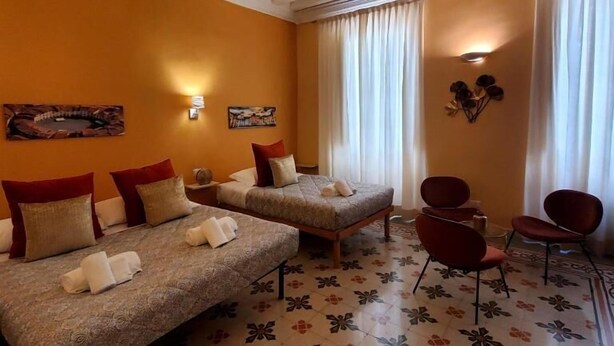 Habitación de hotel con dos camas, un sofá, una silla y un adorno en la pared.