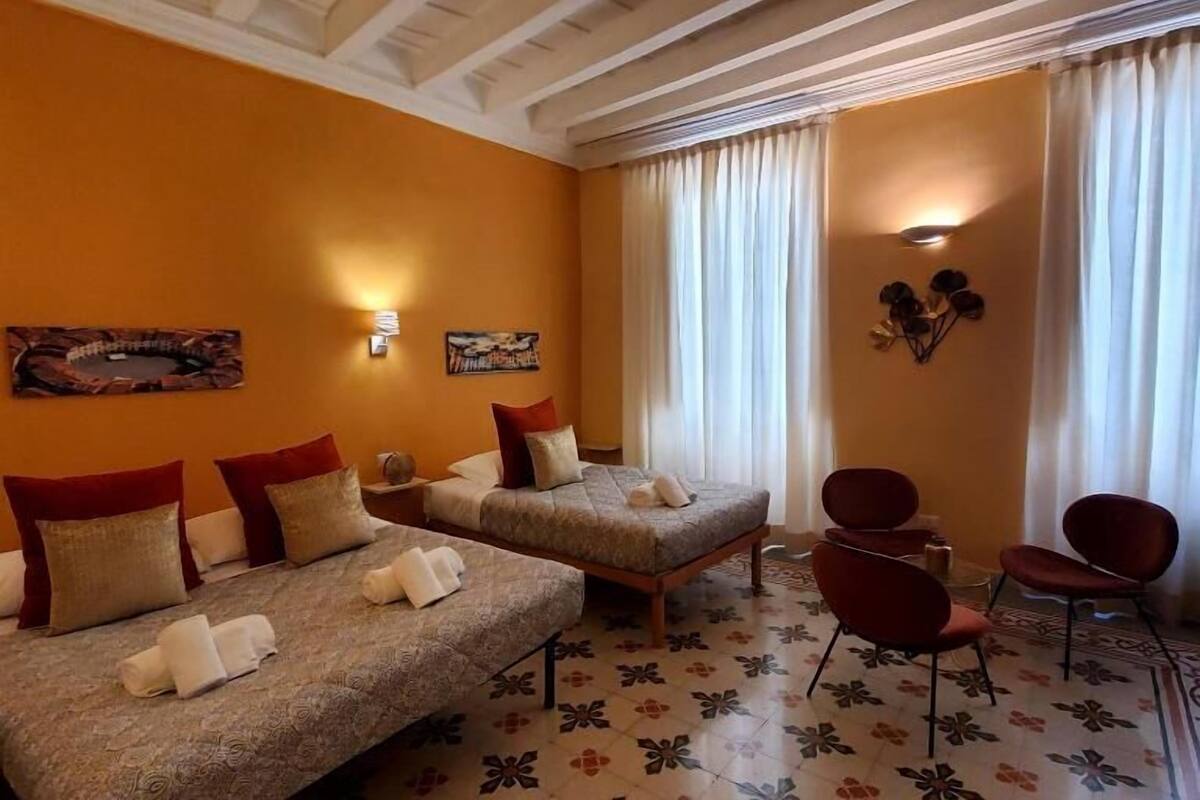A hotel room with two beds, a sofa, a chair, and a decorative wall.