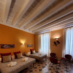 A hotel room with two beds, a sofa, a chair, and a decorative wall. - Residenza FillAnfi (Lucca)