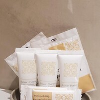 Un set di articoli da toilette con tre flaconi di shampoo da doccia e una saponetta profumata.